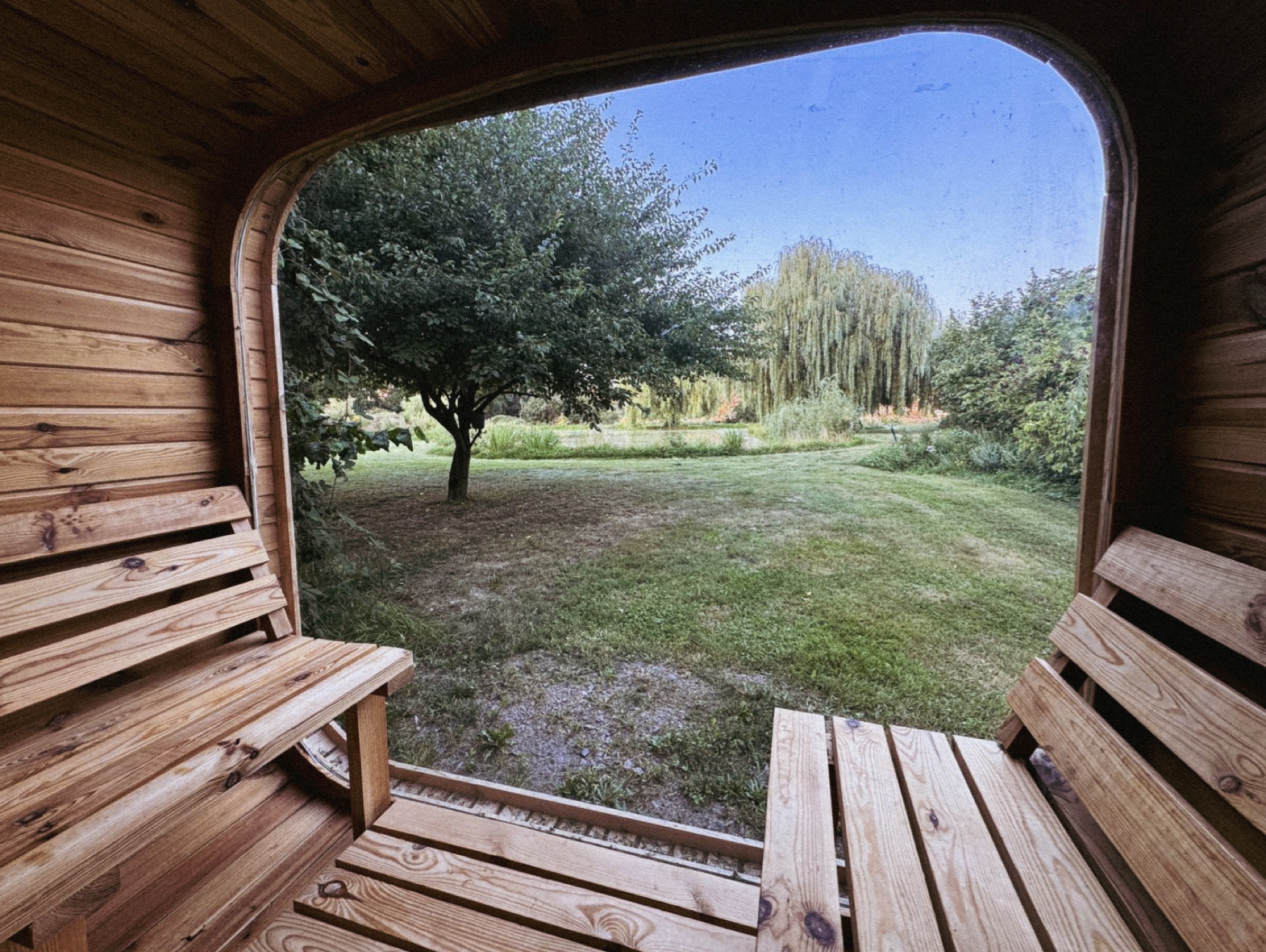 Blick durch das Panoramafenster der Sauna auf Wiese und Weiden